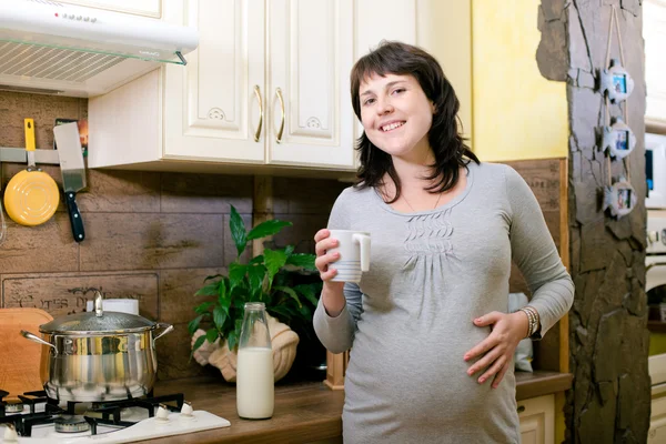Piękna kobieta w ciąży z filiżanką mleka — Zdjęcie stockowe