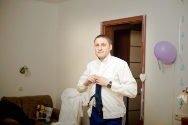 yakışıklı bir genç adam bir gömlek ve kravat takıyor.