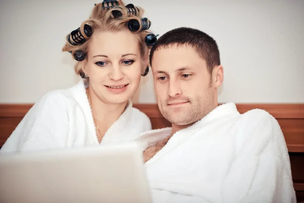 Молодая пара работает дома в постели — стоковое фото