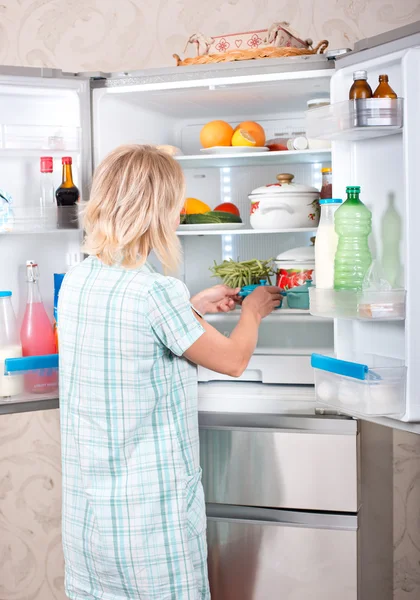 Junge Mutter mit Kind holt Lebensmittel aus dem Kühlschrank. — Stockfoto