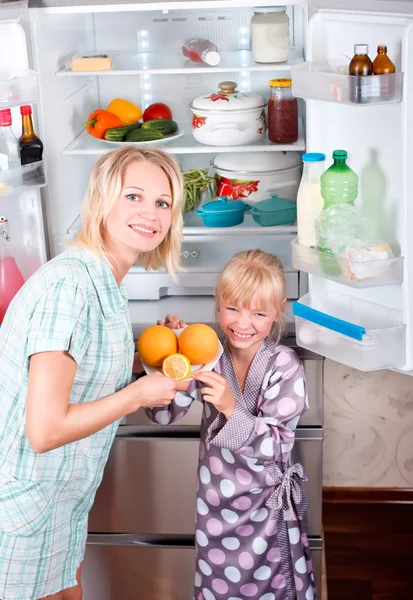 Giovane madre con un bambino prende il cibo dal frigorifero . — Foto Stock