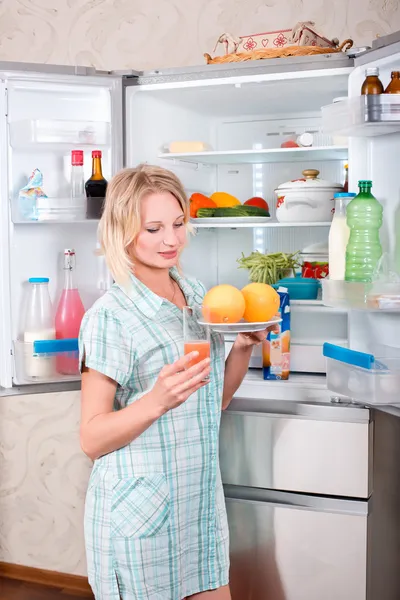 Unga vackra tjej tar mat ur kylskåpet. — Stockfoto