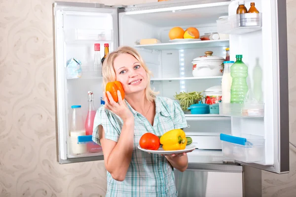 Unga vackra tjej tar mat ur kylskåpet. — Stockfoto