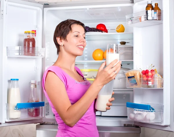 Young beautiful girl takes food from the refrigerator. — Stock Photo, Image