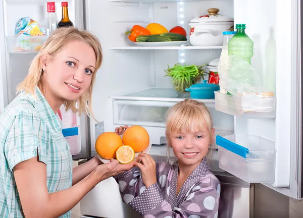 Giovane madre con un bambino prende il cibo dal frigorifero . — Foto Stock