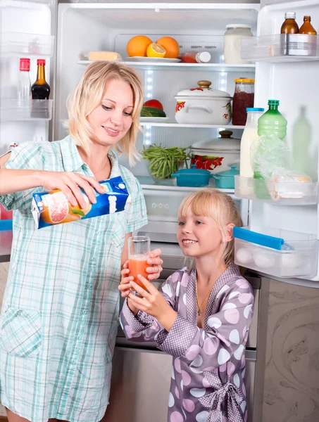 Une jeune mère avec un enfant sort la nourriture du réfrigérateur . — Photo