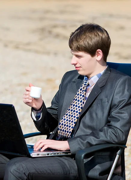En man som arbetar på en dator utomhus. — Stockfoto