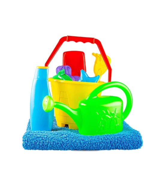 Children's Emmertje voor speelgoed, spade, zonnebrandcrème en handdoek op witte achtergrond — Stockfoto