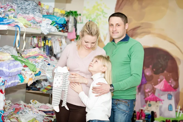 Pregnant woman buying baby clothes in supermarket .  Young pregnant woman choosing newborn clothes — Stock Photo, Image