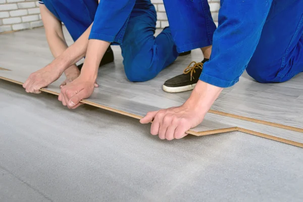 Jóvenes hombres guapos establecido laminado revestimiento de suelo, realizar reparaciones — Foto de Stock