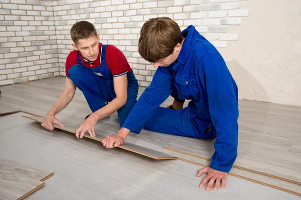 Homens bonitos jovens colocaram revestimento de piso laminado, realizar reparos — Fotografia de Stock