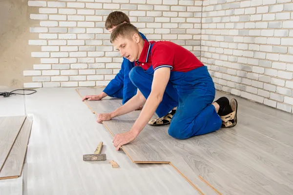 Homens bonitos jovens colocaram revestimento de piso laminado, realizar reparos — Fotografia de Stock