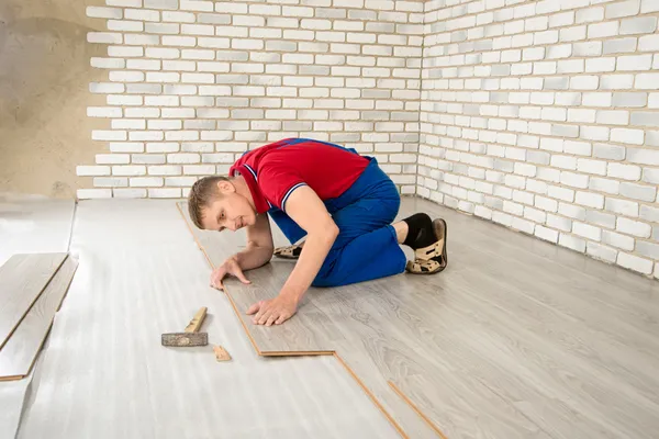 Homens bonitos jovens colocaram revestimento de piso laminado, realizar reparos — Fotografia de Stock