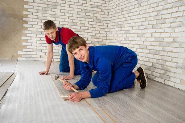 Young handsome men laid laminate floor covering, perform repairs — Stock Photo, Image