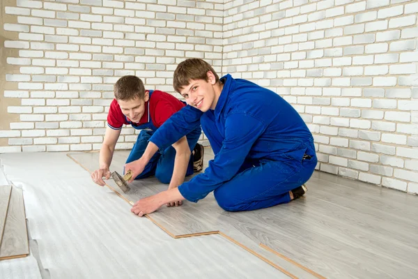 Jóvenes hombres guapos establecido laminado revestimiento de suelo, realizar reparaciones — Foto de Stock