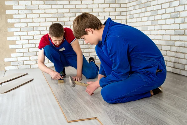 Homens bonitos jovens colocaram revestimento de piso laminado, realizar reparos — Fotografia de Stock