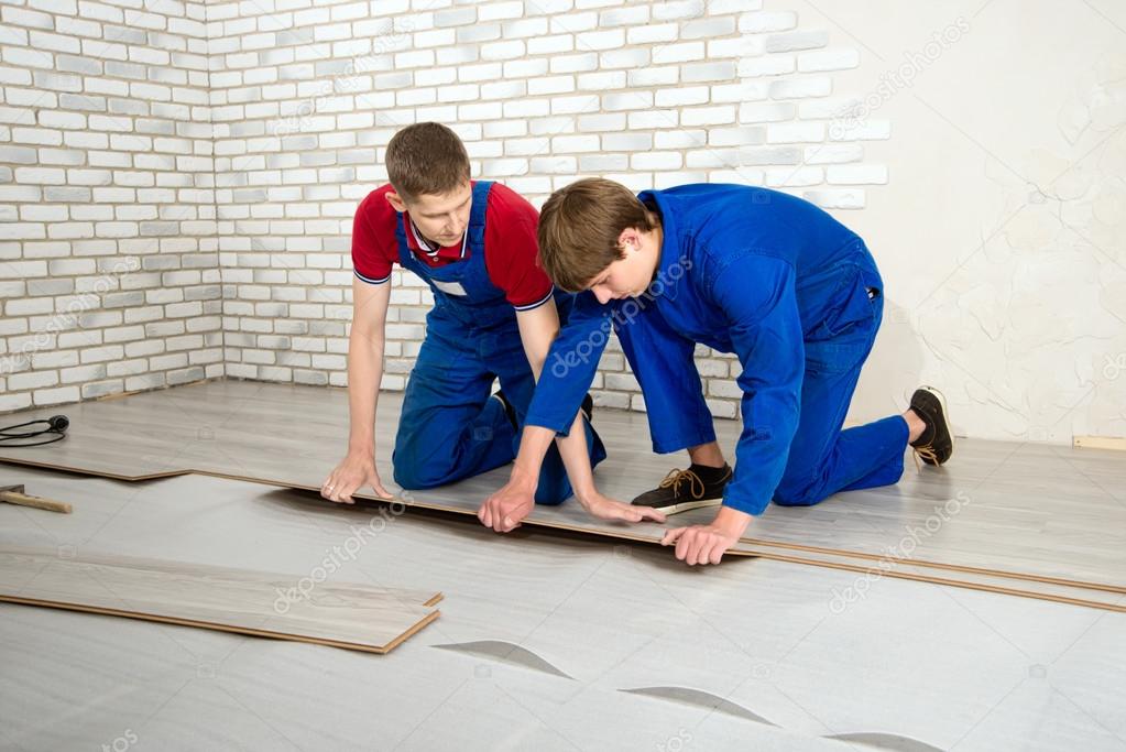 Young handsome men laid laminate floor covering, perform repairs