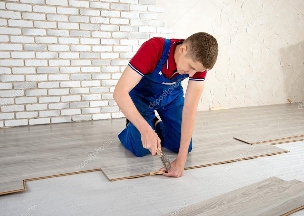 Young handsome men laid laminate floor covering, perform repairs