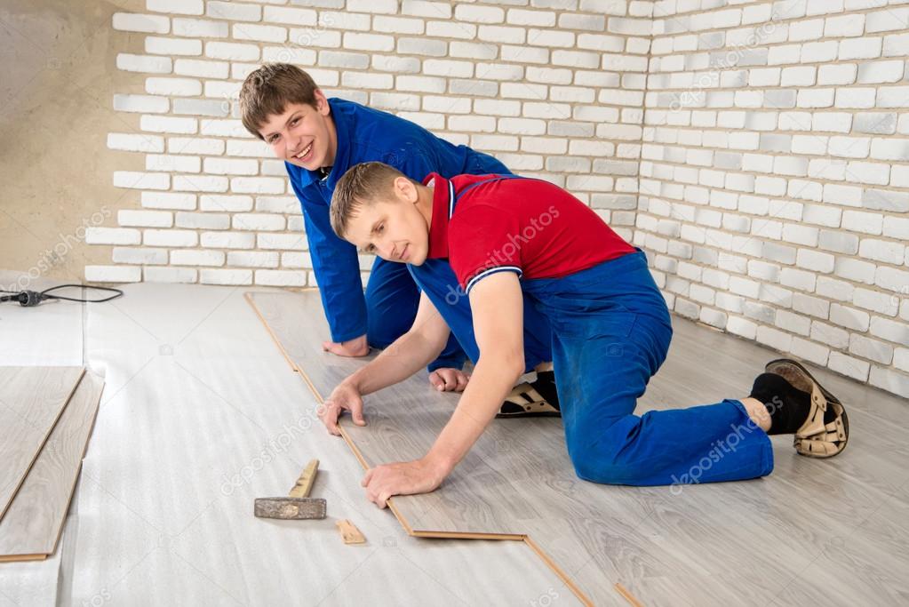 Young handsome men laid laminate floor covering, perform repairs