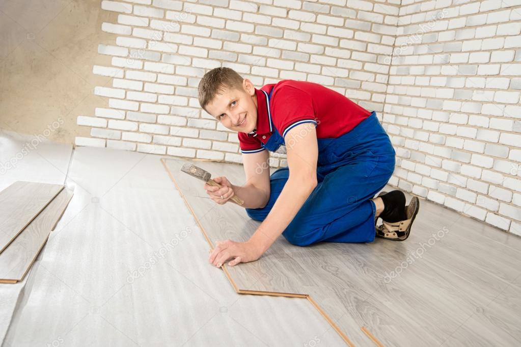 Young handsome men laid laminate floor covering, perform repairs