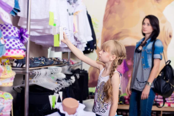 Söt vacker liten flicka med sin mamma att köpa kläder i sho — Stockfoto