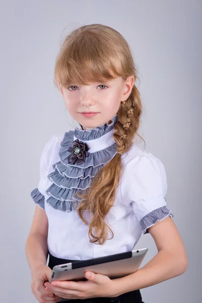 Little schoolgirl smiling while using digital tablet at desk — Stock Photo, Image