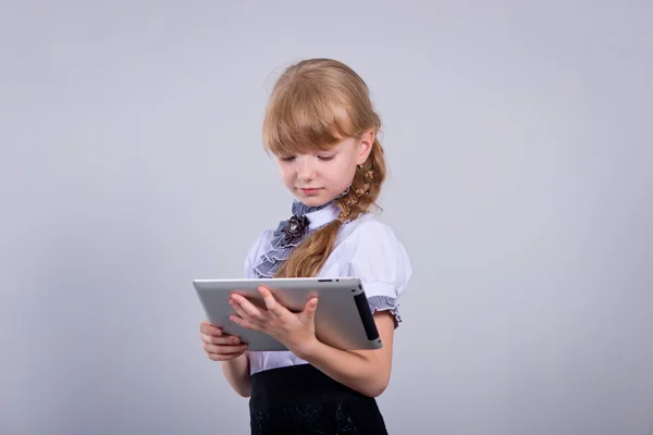 Pequena colegial sorrindo enquanto usa tablet digital na mesa — Fotografia de Stock