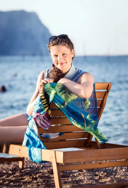 Junges schönes Mädchen liegt auf einer Chaiselongue am Strand — Stockfoto