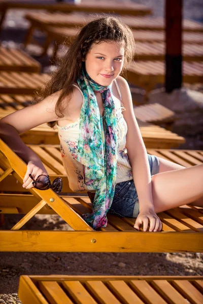 Jeune belle fille allongée sur une chaise longue sur la plage — Photo