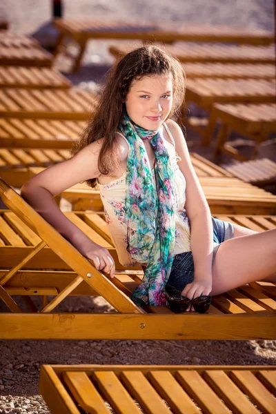 Mooi meisje liggend op een chaise lounge op het strand — Stockfoto