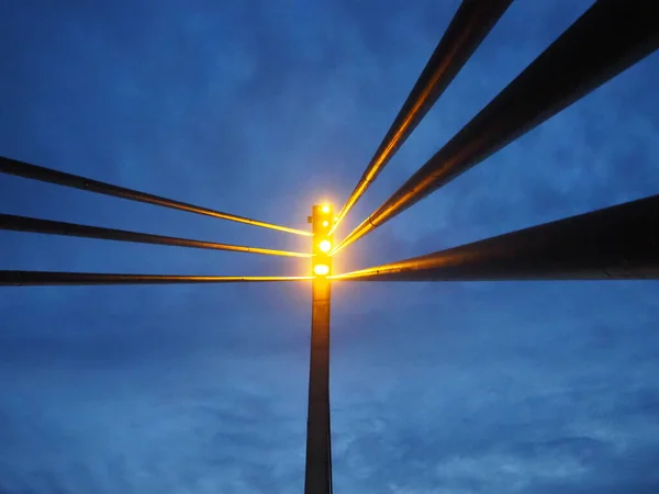 Proyectores en el puente. Torre de luz led portátil. Puente peatonal de San Ireneo sobre el río Sava, Sremska Mitrovica, Serbia. Cielo azul de noche con nubes. Pilares y vigas metálicas, perspectiva — Foto de Stock