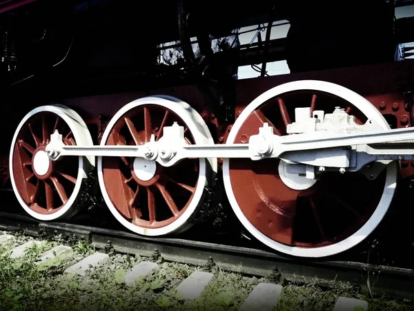 Egy mozdony vagy vonat retro vintage kerekei közelednek. Piros nagy nehézfém kerekek dugattyús vezetőmechanizmussal. A 19-20. századi mozdony gőzmozdonnyal. Élénk fénykép — Stock Fotó