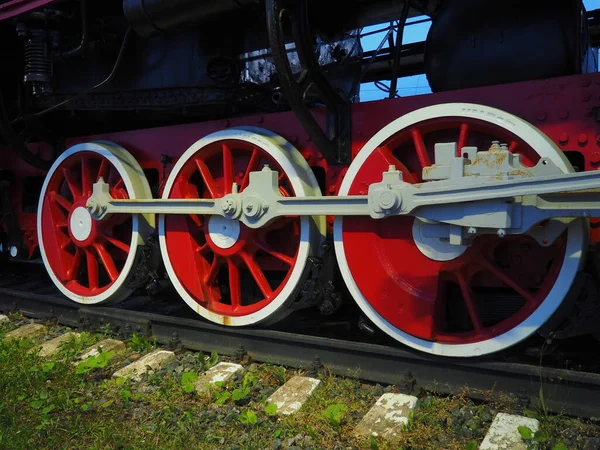 Ruedas retro vintage de una locomotora o tren de cerca. Ruedas rojas grandes de metal pesado con mecanismos de guía de pistón. Locomotora de los siglos XIX-XX con una máquina de vapor. Brillante foto viva —  Fotos de Stock