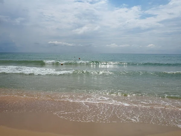 夏日的大海有着平缓的海浪,蓝天的沙滩和自由的空间.柔和的蓝色海浪或清澈的大海上干净的沙滩夏季的概念。美丽的海滩风景。海水上的泡沫 — 图库照片