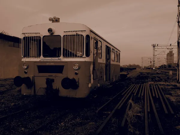 Carro del treno retrò. Locomotiva vintage prodotta in Jugoslavia. Sremska Mitrovica, Serbia. Seppia. Il corpo metallico di un veicolo ferroviario. Rotaie arrugginite. Stazione ferroviaria in prospettiva. — Foto Stock