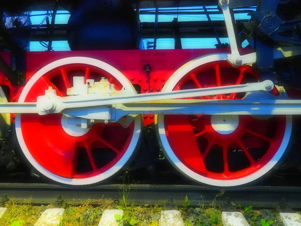 Ruedas retro vintage de una locomotora o tren de cerca. Ruedas rojas grandes de metal pesado con mecanismos de guía de pistón. Locomotora de los siglos XIX-XX con una máquina de vapor. Brillante foto viva —  Fotos de Stock