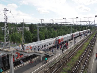 Svir, Rusya 6 Ağustos 2021. Yolcu treni. Trenden inen insanlarla dolu bir platform, manzaralı. Korkuluklar ve uykucular. Stopover. Yolu geçmek için rayların üstündeki merdiven. Yaz günü