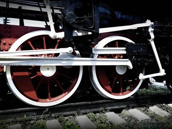Rodas vintage retro de uma locomotiva ou trem de perto. Vermelho grandes rodas de metal pesado com mecanismos de guiamento de pistão. Locomotiva dos séculos XIX-XX com um motor a vapor. Foto vívida brilhante — Fotografia de Stock