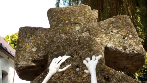 Skeleton zombie ruce zvedající se ze hřbitova, Halloween. Kosti rukou kostlivce na náhrobku. Mrtvý muž, který přišel k životu. Starý křesťanský hřbitov a kamenný mech kříž — Stock video
