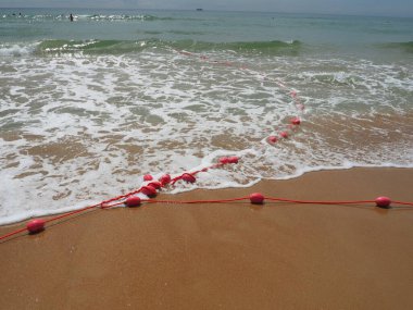 Şamandıralar deniz suyunda ipte. Cankurtaranlar, insanları suyun derinliği konusunda uyarmak için pembe kemerlerdir. Boğulmanın kurtarılması. Kumsalda oteller arasında bir yeri sınırlandırmak. Kabarcıklı dalga