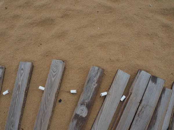 Деревянный пешеходный мост на песчаном пляже. Неровные, влажные деревянные доски, скрепленные вместе. Край пляжного сезона в отеле. Никаких людей, скопируйте пространство. Оснащен песчаным пляжем после шторма или циклона. Туризм — стоковое фото