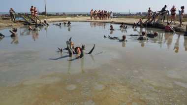 Anapa Russia August 28 2021 Hill mud, a product of the eruption of mud volcanoes. Volcano crater, Hephaestus mud volcano. People bathe and enjoy themselves in liquid, thick clay. Men and women smeared clipart