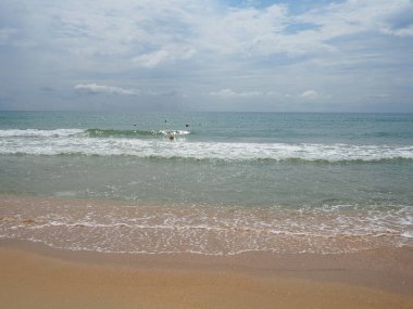 Yumuşak dalgalı, mavi gökyüzü kumlu ve serbest alanlı yaz denizi. Yumuşak mavi okyanus dalgası ya da temiz kumsalda açık deniz yaz konsepti. Muhteşem bir sahil manzarası. Deniz suyunda köpük