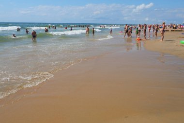 Anapa, Rusya, 20 Ağustos 2021 Yaz günü plajda. İnsanlar yüzüyor, güneşleniyor, güneşin ve Karadeniz 'in tadını çıkarıyor. Köpüklü dalgalar. Sahilleri ayırmak için halat üzerinde şamandıralar.