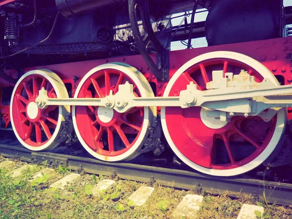 Ruedas retro vintage de una locomotora o tren de cerca. Ruedas rojas grandes de metal pesado con mecanismos de guía de pistón. Locomotora de los siglos XIX-XX con una máquina de vapor. Estilo retro —  Fotos de Stock