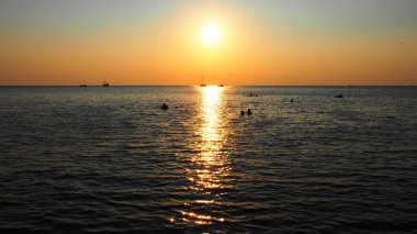Anapa, Rusya 23 Ağustos 2021 Deniz üzerinde Gün Batımı. Gün batımında güzel dalgalar. Turist Mekke, tatil köyü. Akşam gökyüzü. Işınlar sudan yansıyor. Gemiler ve insanlar denizde yüzüyor.