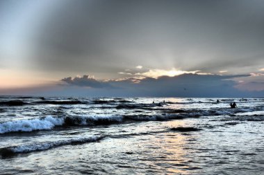 Köpüklü dalgalar. Güzel gün batımı. Köpüklü dalgalar kumlu sahilde yuvarlanıyor. Vityazevo, Anapa, Karadeniz. Turist Mekke, sağlık merkezi. Akşam gökyüzünde renkli bulutlar. Işınlar sudan yansıyor.