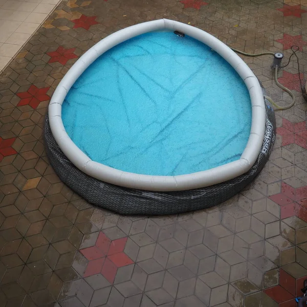 Piscina redonda de borracha cheia de água. Água azul na piscina. Grandes gotas de chuva caem na superfície da água. Tempo chuvoso no hotel. Ninguém na piscina devido ao mau tempo — Fotografia de Stock