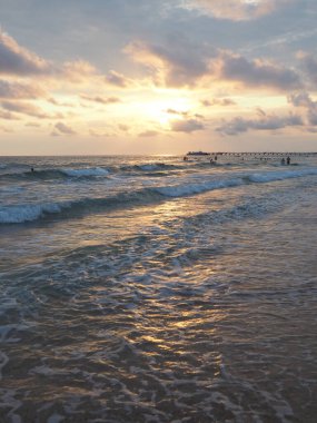Dalgalar ve gün batımı. Güzel gün batımı. Köpüklü dalgalar kumlu sahilde yuvarlanıyor. Vityazevo, Anapa, Karadeniz. Turist Mekke, sağlık merkezi. Akşam gökyüzü. Işınlar sudan yansıyor..