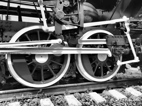 Treno retrò due ruote. Traverse e rotaie, meccanismi, pistoni e guide. Locomotiva dell'inizio del XIX secolo con motore a vapore. Stile vintage. Nero - fotografia bianca. Bella carta. — Foto Stock